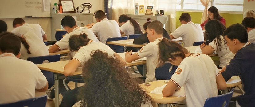 Estudiantes dentro de un salón de clases, tomando una prueba del College Board